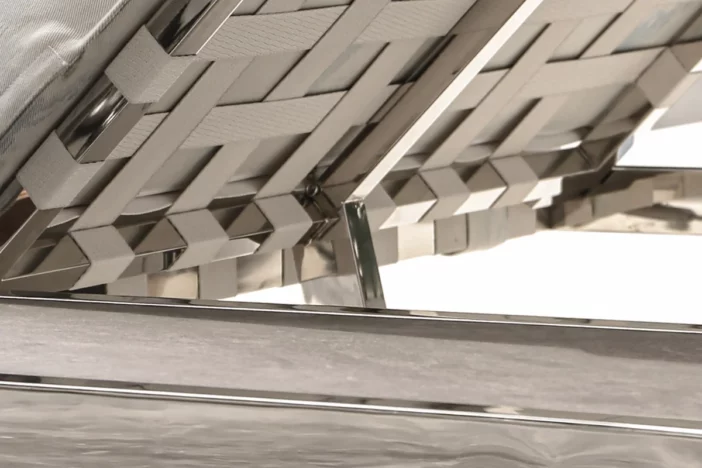 Close-up of the back of a shiny stainless steel sunlounger with off-white straps
