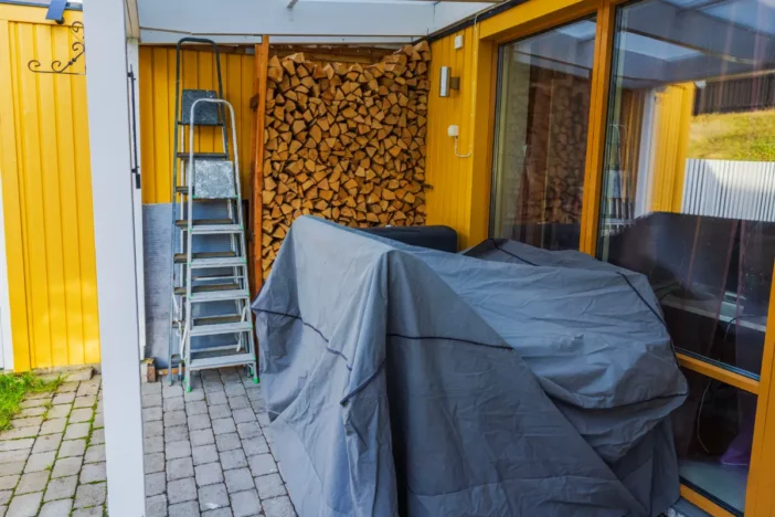 Sheltered brick patio with outdoor furniture covered by a protective black tarp