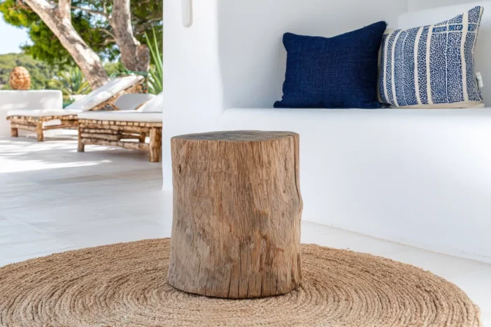 Tree stump table on a tan round rug on a granite paver patio