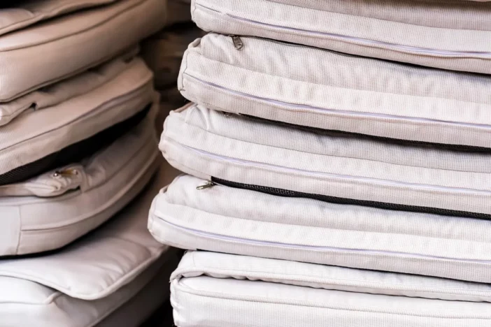 Stacked thin white outdoor seat cushions with zippers