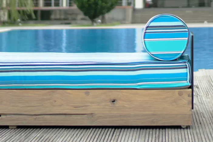 Close-up of sunlounger with wooden base and striped aqua cushions