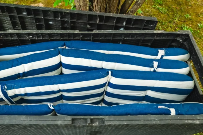 Open storage container with striped. blue and white lawn furniture cushions