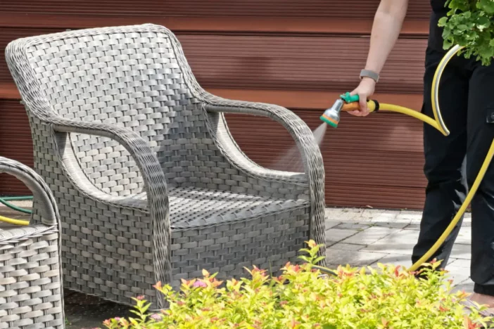 Grey wide weave resin wicker armchair being sprayed with water