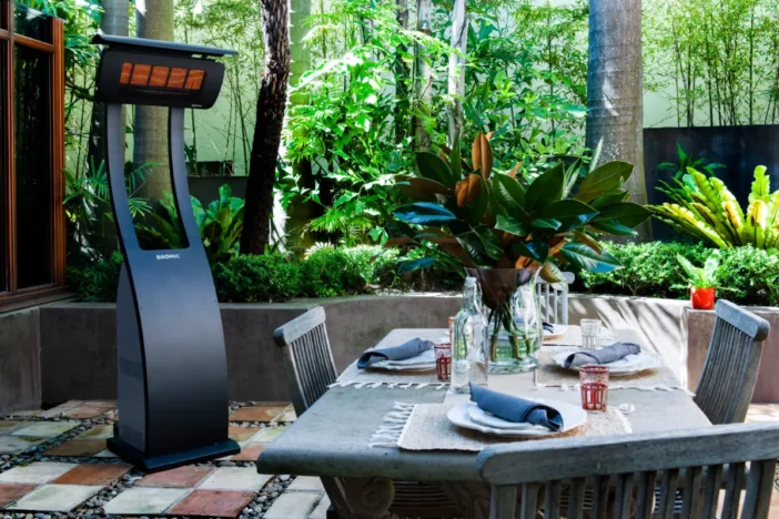 Modern freestanding patio heater set away from an outdoor dining set
