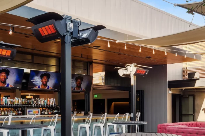Black gas patio heaters mounted on poles at an outdoor bar