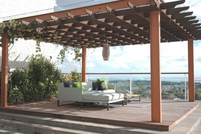 Large wooden pergola with white upholstered lounge set overlooking a valley