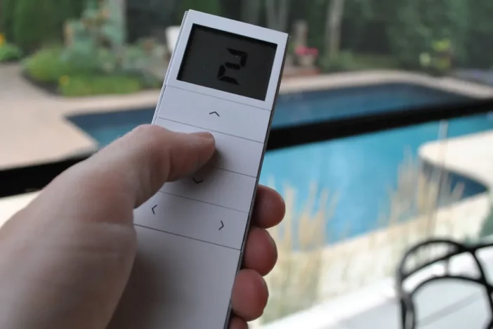Hand using a modern remote control to adjust an outdoor shade screen