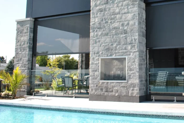 Black automatic screens partially drawn to shade loggia near a pool