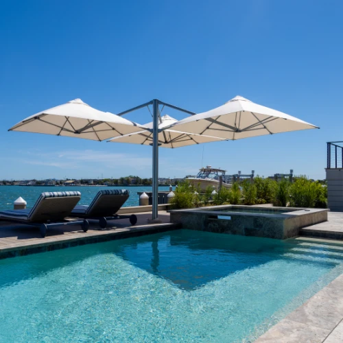 Multi-canopy patio umbrella with square off-white fabric and LED light by water