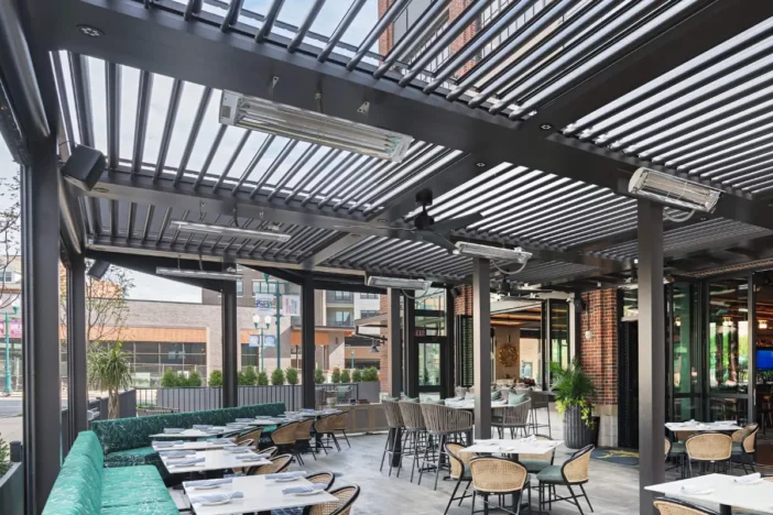 Large black modern pergola with heaters over a restaurant patio dining area
