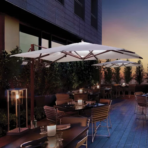 Cantilever umbrella with square white canopy, mounted heaters and LED light at night