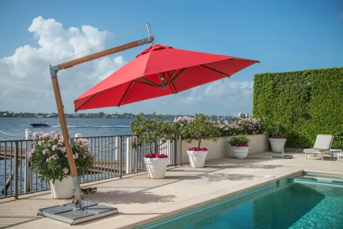 Angular bamboo cantilever umbrella with red octagonal canopy and paver base poolside