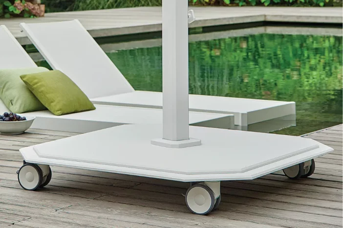 White powder-coated steel patio umbrella base with wheels on a hardwood deck