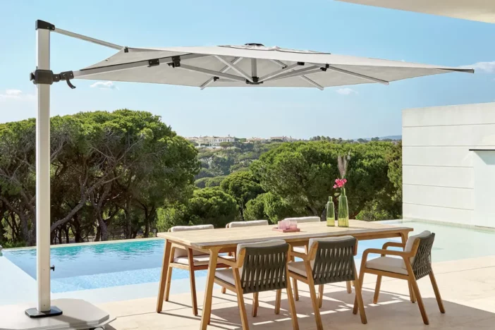 Silver cantilever umbrella with square white canopy over a dining set