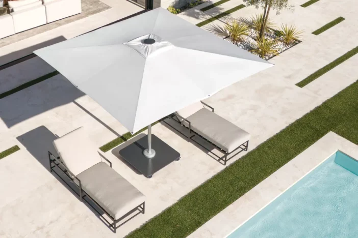 White canopy patio umbrella with a square dark grey base poolside shading sunlounger
