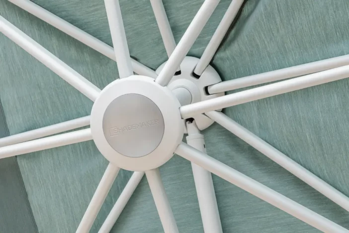 Detailed view of a white patio umbrella hub and rib assembly with a light teal fabric canopy