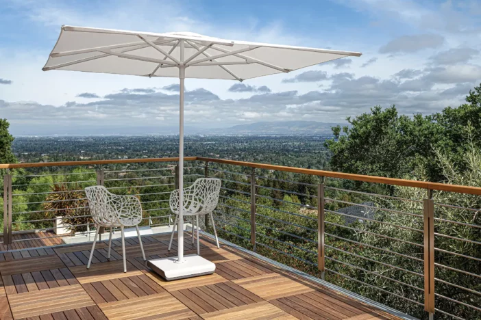 White market umbrella and freestanding base on a hardwood deck with a scenic view