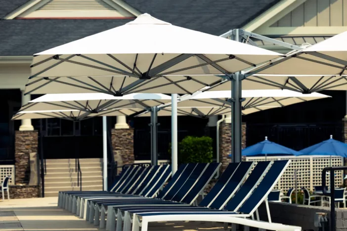 Quad-canopy offset umbrellas with silver frames and square white canopies shading sunloungers