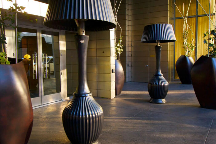 Two tall Kindle Living floor‑lamp style patio heaters with ribbed bodies and shades at a hotel entry