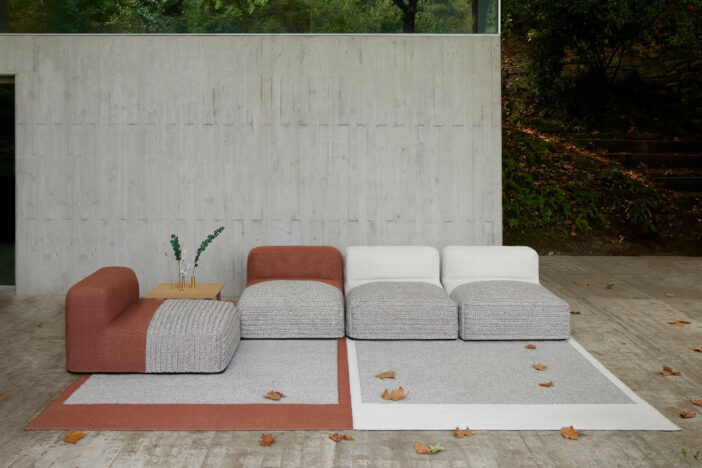 Dark salmon, warm grey, and off‑white GAN outdoor rugs with matching minimalist sectional seating on a modern patio