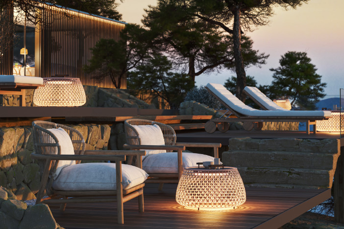 Split‑level deck with illuminated woven side tables and lounge seating at dusk