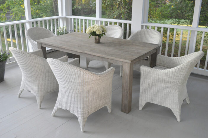 Modern white‑grey outdoor wicker dining armchairs around a light wood rectangular table on a porch with forest view