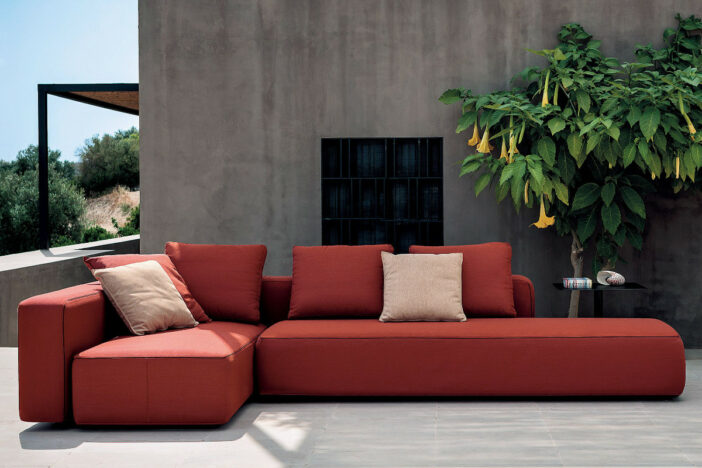Tomato red minimalist outdoor sectional with cream accent pillows on a concrete patio
