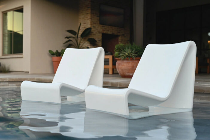Two white plastic lounge chairs with minimalist ergonomic design set in a swimming pool