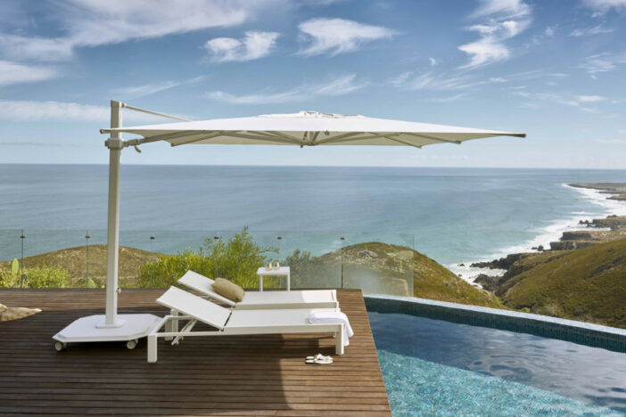 White Jardinico cantilever umbrella shading sunloungers on a deck overlooking the water