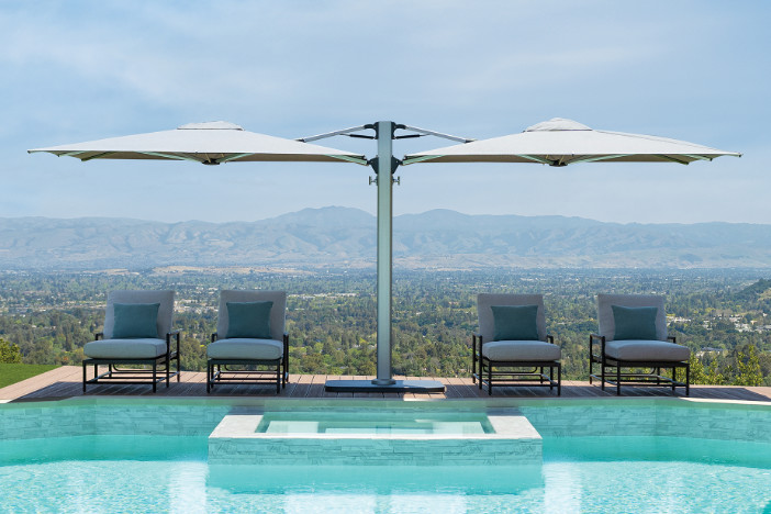 Dual canopy Shademaker cantilever umbrella with white canopies shading poolside sunloungers
