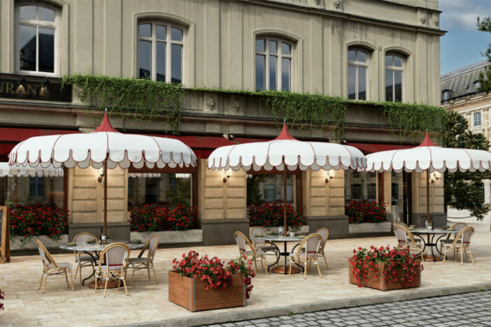 Decorative market umbrellas with white scalloped valances and red accents shade sidewalk cafe tables