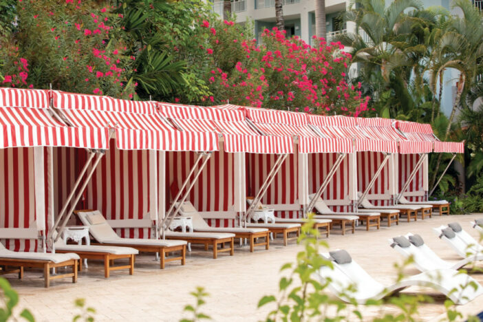 Row of red and white striped cabanas with wood-framed sunloungers