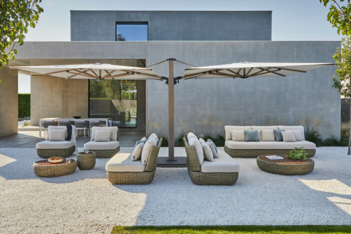 Dual-canopy cantilever umbrella shading separate lounge sets on a gravel backyard patio