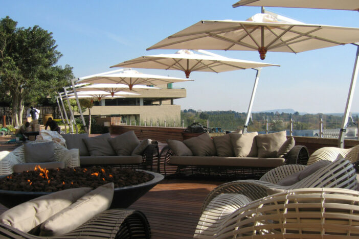 Cantilever umbrellas with square off-white canopies shading modern lounge sets on a hardwood terrace
