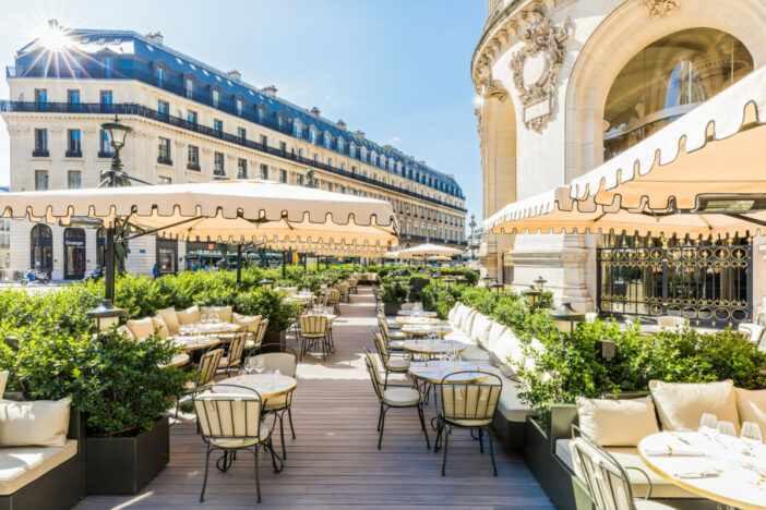 Square cantilever umbrellas with cream-colored canopies and valances shade an elegant French restaurant patio
